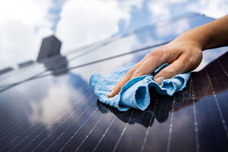 Homme essuyant délicatement ses panneaux solaires avec un chiffon doux