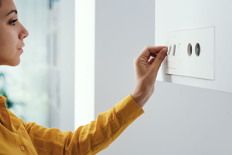 Femme ajustant la température de sa pompe à chaleur eau-eau